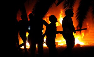 File - Libyan civilians watch fires in Ansar al-Shariah Brigades compound, after hundreds of Libyans, Libyan Military, and Police raided the Brigades base, in Benghazi, Libya, Friday, Sept. 21, 2012. The recent attack that killed the U.S. ambassador and three other Americans has sparked a backlash among frustrated Libyans against the heavily armed gunmen