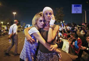 Passengers embrace each other as they wait outside Istanbul's Ataturk airport, early Wednesday, June 29, 2016 following their evacuation after a blast.