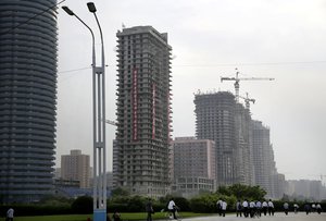 In this Monday, June 27, 2016, photo, North Korean men cycle, while others walk past buildings under construction on “Ryomyong Street,” in Pyongyang, North Korea.