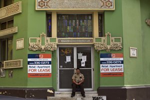 In this Aug. 2, 2015 file photo, a private security guard sits in front of a closed down business in the colonial district of Old San Juan, Puerto Rico.