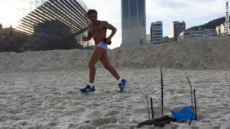 A runner passes by the body parts that were found near the Olympics beach volleyball stadium, visible in the background.