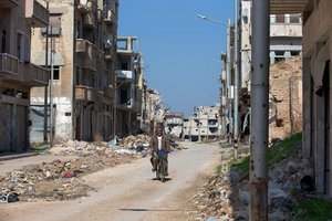 File - In this picture taken Friday, Feb. 26, 2016, a Syrian man rides a bicycle through a devastated part of the old city of Homs, Syria. Some 1,200 rebels and civilians, many of them wounded and starving from a yearlong siege, withdrew from the last remaining strongholds in the ancient heart of Homs in May 2014, surrendering to President Bashar Assad a bloodstained city once dubbed the “capital of the revolution.”