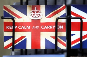 A postcard reading "Keep Calm and Carry On" sits in a rack outside a newsagent in London, U.K., on Tuesday, June 28, ...