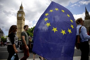 A remain supporter stops to talk to people as he walks around with his European flag across the street from the Houses of Parliament in London, Friday, June 24, 2016.