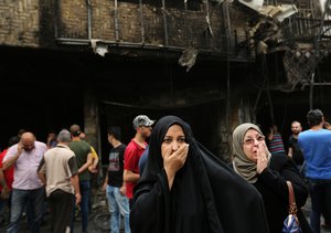 Iraqi women wait for their family members who are missing after a car bomb went off in a commercial area in Karada neighborhood, Baghdad, Iraq, Sunday, July 3, 2016.