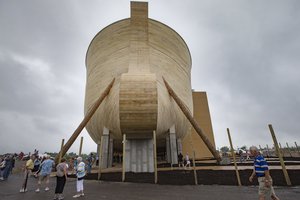 Visitors roam around a replica Noah's Ark as rain clouds pass overhead at the Ark Encounter theme park during a media preview day