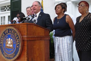 Gov. John Bel Edwards speaks at a podium with Baton Rouge lawmakers as he announces the U.S. Justice Department's civil rights division would lead an investigation into the police killing of a black man, Alton Sterling, in the city, on Wednesday, July 6, 2016, in Baton Rouge, La.