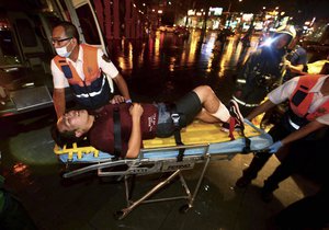 An injured man is helped by emergency rescue workers after an explosion on a passenger train in Taipei, Taiwan, Thursday, July 7, 2016.