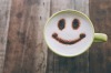 Happy face on coffee cup on wooden background with vintage colour effect. Still life.