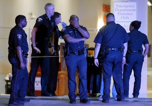 A Dallas police officer covers his face as he stands with others outside the emergency room at Baylor University Medical Center, Friday, July 8, 2016, in Dallas. Snipers opened fire on police officers in the heart of Dallas on Thursday night, killing some of the officers.