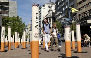 A couple walk through an anti-tobacco installation set up by the Uruguay's Resources National Fund, depicting cigarettes' harmful components, in Montevideo, Uruguay, Monday, Nov. 15, 2010. Philip Morris International Inc., the world's second-biggest cigarette company, is pursuing a claim before World Bank arbitrators alleging that Uruguay is violating its trade agreement