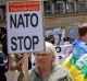 A woman holds a banner during an anti-NATO protest joined by hundreds in Warsaw, Poland, on Saturday.