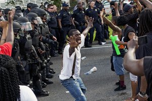 A man attempts to stop protesters from engaging with police in riot gear in front of the Baton Rouge Police Department headquarters after police attempted to clear the street in Baton Rouge, La., Saturday, July 9, 2016.