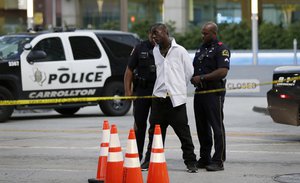 A man is detained by police, Monday, July 11, 2016, in Dallas, after he knocked over a news station's video camera near the site where a sniper killed five police officers on Thursday night.