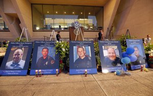 Portraits of the five fallen police officers sit in front of a stage after a candle light vigil in front of city hall honoring them, Monday, July 11, 2016, in Dallas.