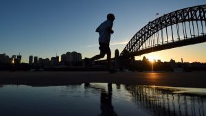 A man goes for an early morning run as the sun rises over Walsh Bay on Wednesday 13 July.