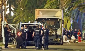 Police stand by as medical personnel attend a person on the ground, right, in the early hours of Friday, July 14, 2016, on the Promenade des Anglais in Nice, southern France, next to the lorry that had been driven into crowds of revelers late Thursday.