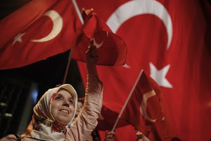 A woman waves Turkish flags during a rally against the attempted coup in Taksim Square in Istanbul, protesting against the attempted coup, Monday, July 18, 2016.