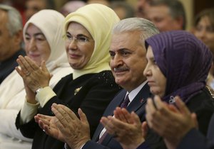 Binali Yildirim, centre,Turkey's Transportation Minister, sitting next to Emine Erdogan, 2nd left, the wife of Turkey's President Recep Tayyip Erdogan, applauds during a meeting in Ankara, Turkey, Tuesday, May 17, 2016.