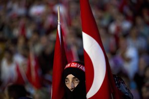 A woman takes part in a pro-government rally as she hold a Turkish flag in Taksim Square, Istanbul, Tuesday, July 19, 2016.