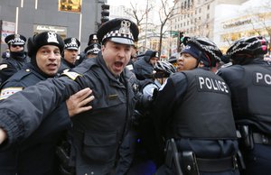 Chicago Police officer yells at reporters and photographers to get back as officers take into custody a protester during a scuffle at a bicycle barricade on Chicago's Magnificent Mile Thursday, Dec. 24, 2015, in Chicago.