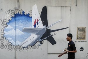 FILE - In this Tuesday, Feb. 23, 2016, file photo, a waiter walks past a mural of flight MH370 in Shah Alam outside Kuala Lumpur, Malaysia.