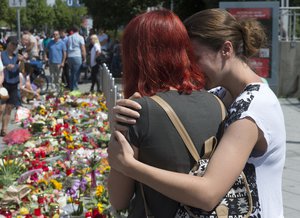 People mourn beside the Olympia shopping center where a shooting took place leaving nine people dead two days ago in Munich, Germany, Sunday, July 24, 2016.