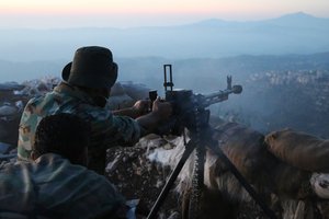 In this photo taken on Saturday, Oct. 10, 2015, Syrian army personnel fire a machine gun in Latakia province, about 12 miles from the border with Turkey, Syria.