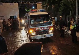 Police officers stand guard as a convoy of ambulances carrying the bodies of drug traffickers drive past by at Wijaya Pura port upon arrival from the prison island of Nusakambangan in Cilacap, Central Java, Indonesia, Friday, July 29, 2016.