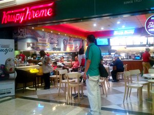 A man stands outside a Krispy Kreme donuts branch.