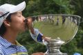 Min Woo Lee kisses the trophy.