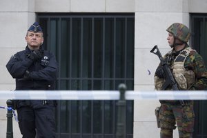 A Belgian police officer and a soldier guard a court building where Salah Abdeslam, the top suspect in last year's deadly Paris attacks, was expected to appear before a judge in Brussels, Belgium, Thursday, March 24, 2016.