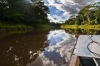 The bow of a touring skiff cruises along the calm waters of the Amazon.