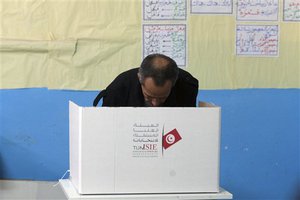 A Tunisian prepares his ballot to vote in a polling station in Tunis, Tunisia, Sunday Dec. 21 , 2014. Tunisians voted on Sunday for a new president in a runoff between a symbol of the country's previous regimes and a veteran human rights activist who came to power after the revolution of 2011.