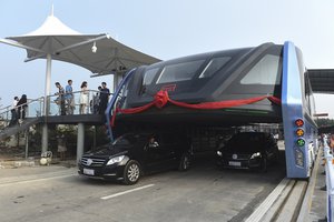 In this Tuesday, Aug. 2, 2016 photo released by Xinhua News Agency, people stand on a platform as the Transit Elevated Bus TEB-1 conducting a test run after it unveiled in Qinhuangdao, north China's Hebei Province.