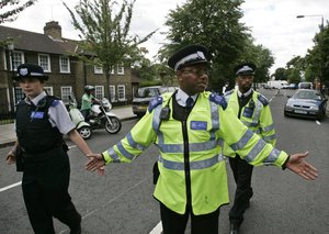 British police officers cordon off the scene of a police raid in an apartment block in west London, Friday July 29, 2005.