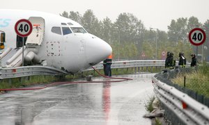 Firefighters work on DHL cargo plane that skidded off a runway at Orio al Serio airport overnight, busting through a perimeter fence and onto a provincial highway, near Bergamo in Northern Italy, Friday, Aug. 5, 2016.