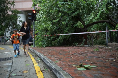 People walk past tree branches broken by strong wind caused by Typhoon Nida in Hong Kong, Tuesday, Aug. 2, 2016.