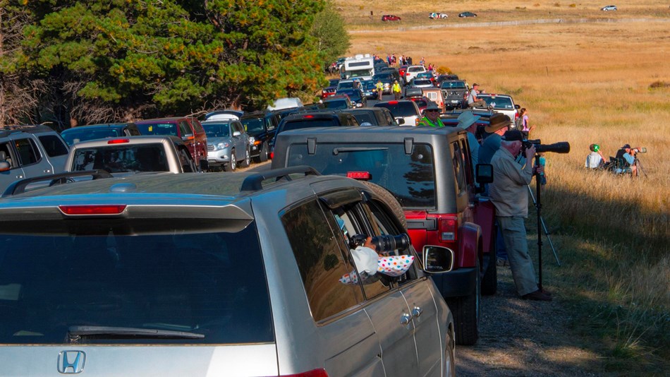 Cars packed on both sides of a road in a mountain valley