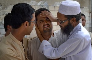 People comfort a man mourning the death of a family member who was killed in suicide bombing, at a funeral in Quetta, Pakistan, Monday, Aug. 8, 2016.