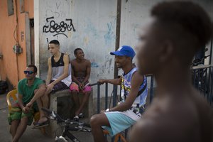 Neighbors chat on the sidewalk next to the house where Brazilian judo gold medalist Rafaela Silva used to live at Cidade de Deus slum in Rio de Janeiro, Brazil, Tuesday, Aug. 9, 2016.