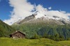 Idyllic Alpine chalet summer mountain meadow panorama Alps, Switzerland.