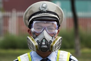 A Chinese traffic police man wears a mask at a security checkpoint near the site of an explosion in northeastern China's Tianjin municipality Saturday, Aug. 15, 2015.