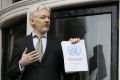 Julian Assange, standing on the balcony of the Ecuadorian embassy in London, holds the UN report saying he has been ...