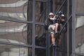 A man scales the all-glass facade of Trump Tower using suction cups.