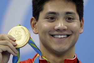 Singapore's Joseph Schooling shows off his gold medal in the men's 100-meter butterfly medals ceremony during the swimming competitions at the 2016 Summer Olympics, Friday, Aug. 12, 2016, in Rio de Janeiro, Brazil.