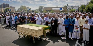 Thousands gather to pray at caskets of Imam Maulama Akonjee, draped in green top, and Thara Uddin in a municipal parking lot, Monday Aug. 15, 2016, in New York.