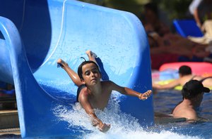 A child enjoys a water slide on a beach near the coastal town of Bodrum, Turkey, Sunday, Aug. 16, 2015.