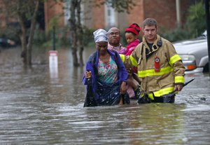 A member of the St. George Fire Department assists residents as they wade through floodwaters from heavy rains in the Chateau Wein Apartments in Baton Rouge, La., Friday, Aug. 12, 2016.