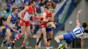 Swans midfielder Tom Mitchell gets a kick away in traffic.